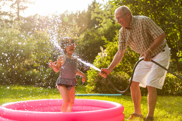 grandfather-with-waterhose-sprays-granddaughter-with-water
