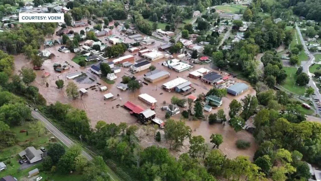 Aerial view of Damascus, Virginia, with muddy floodwaters inundating downtown streets, homes, and businesses amid surrounding trees.